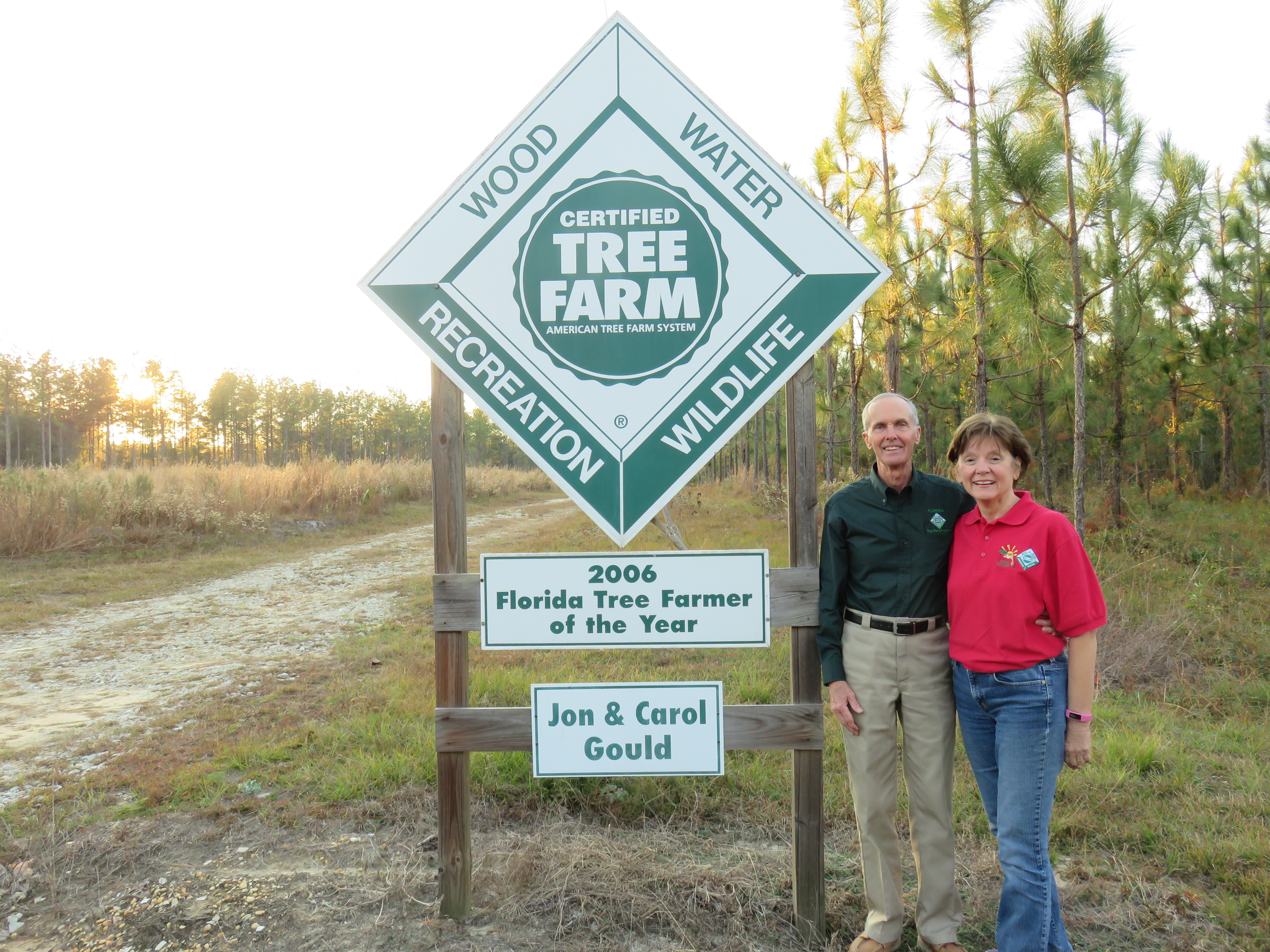 The Goulds standing by their Tree Farm sign
